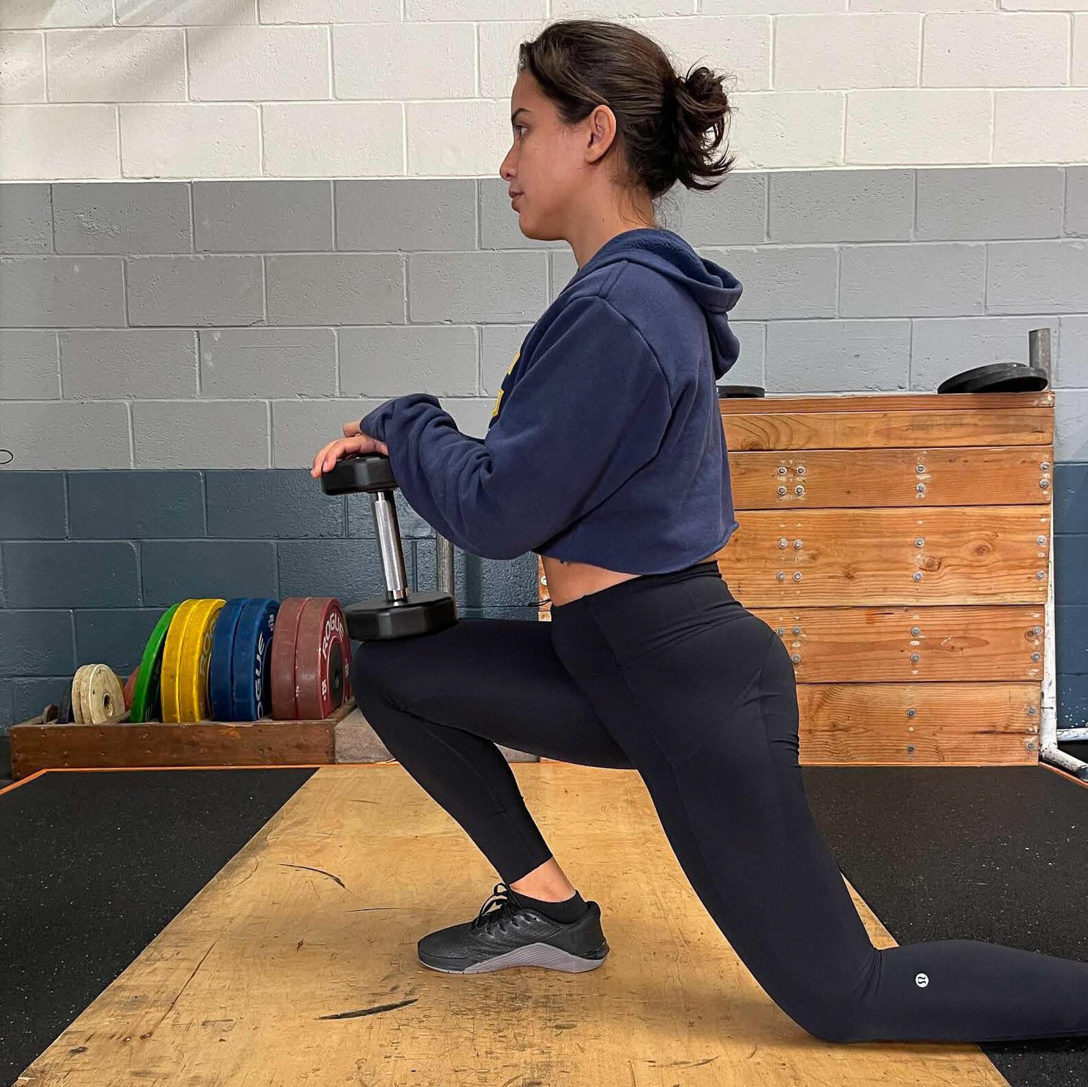 Young woman in kneeling lunge stretching in the gym