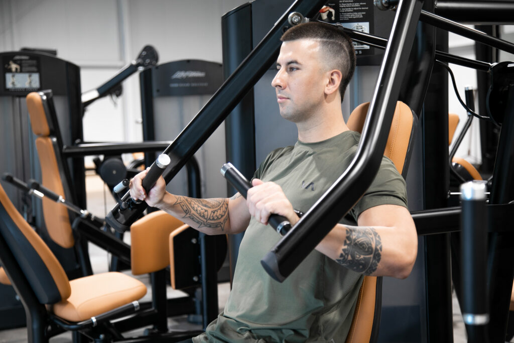 Man sitting on bench press machine at Kilauea Phys Ed